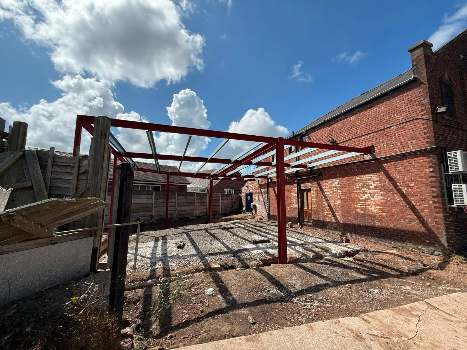 Red structural steel frame beside a brick building