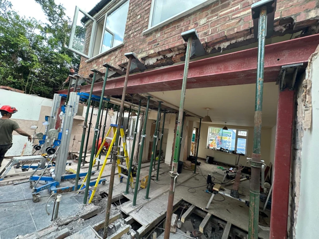 Steel RSJ beam supported by adjustable acrow props during a home renovation and structural wall removal.